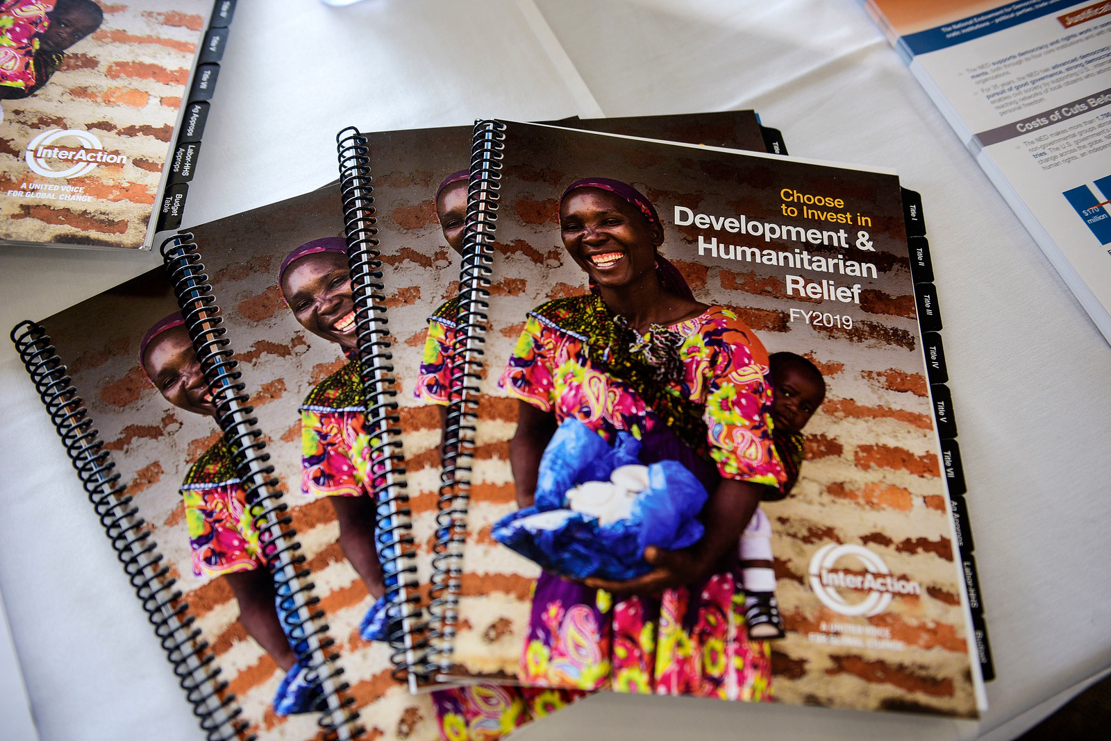 Photo of reports on a table. Report cover shows smiling women carrying mushrooms with a smile child on her back, posing in front of brick wall.