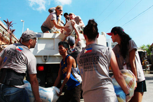 A group of workers load bags of food onto a truck