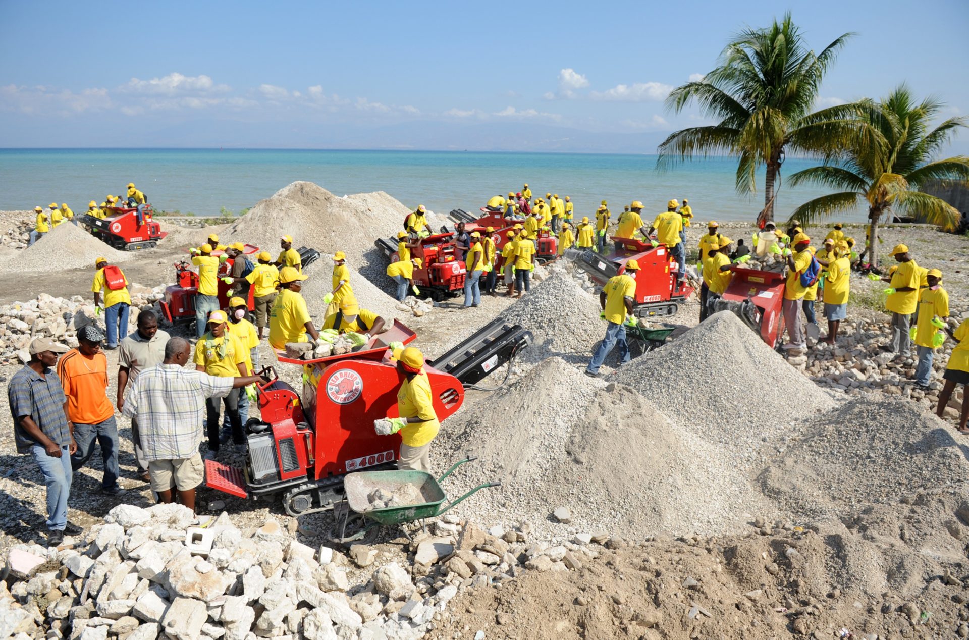 Workers crush rubble with machines on a beach in Haiti