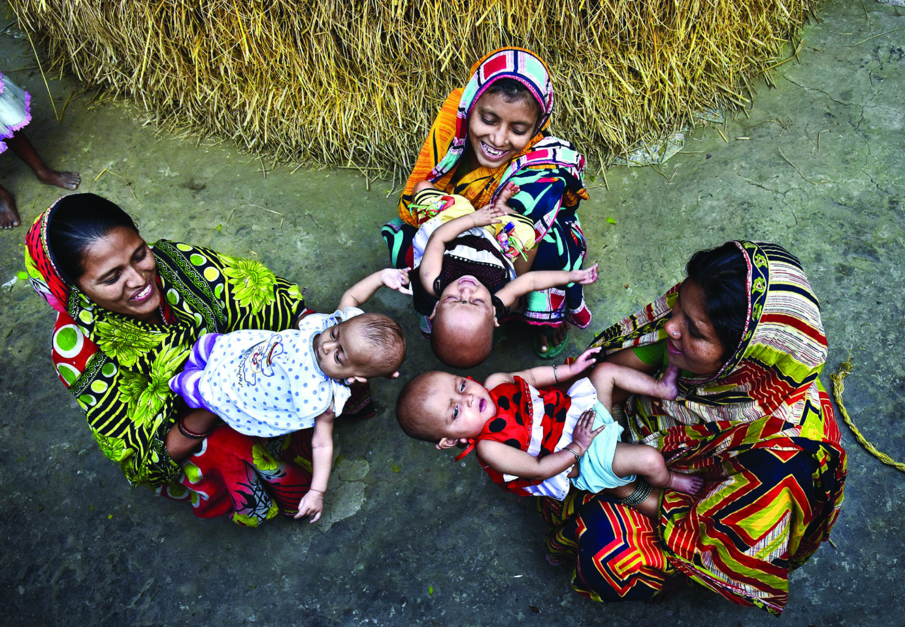 Three mothers site in a circle holding their newborn babies