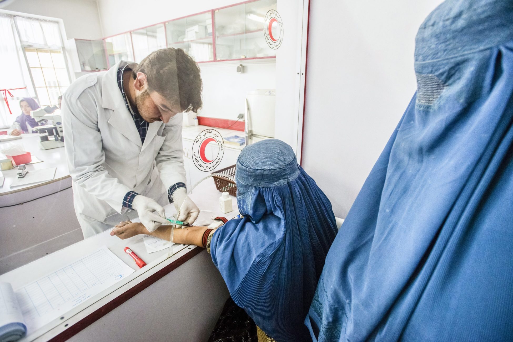Laboratory staff Rohudin draws blood of woman wearing burka for blood test in laboratory of Central Hospital of Afghan Red Crescent Society, Kabul, Afghanistan