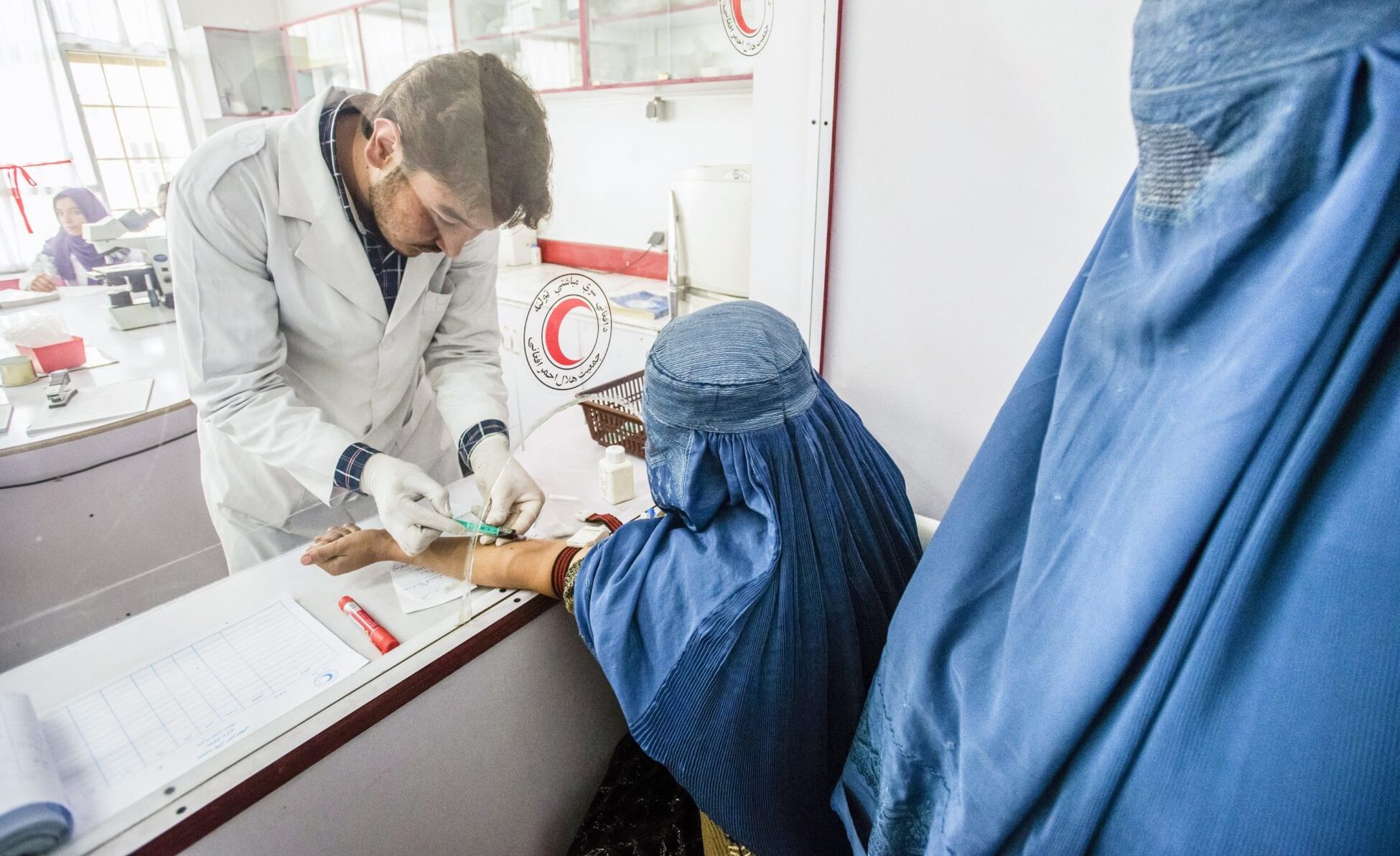 Laboratory staff Rohudin draws blood of woman wearing burka for blood test in laboratory of Central Hospital of Afghan Red Crescent Society, Kabul, Afghanistan