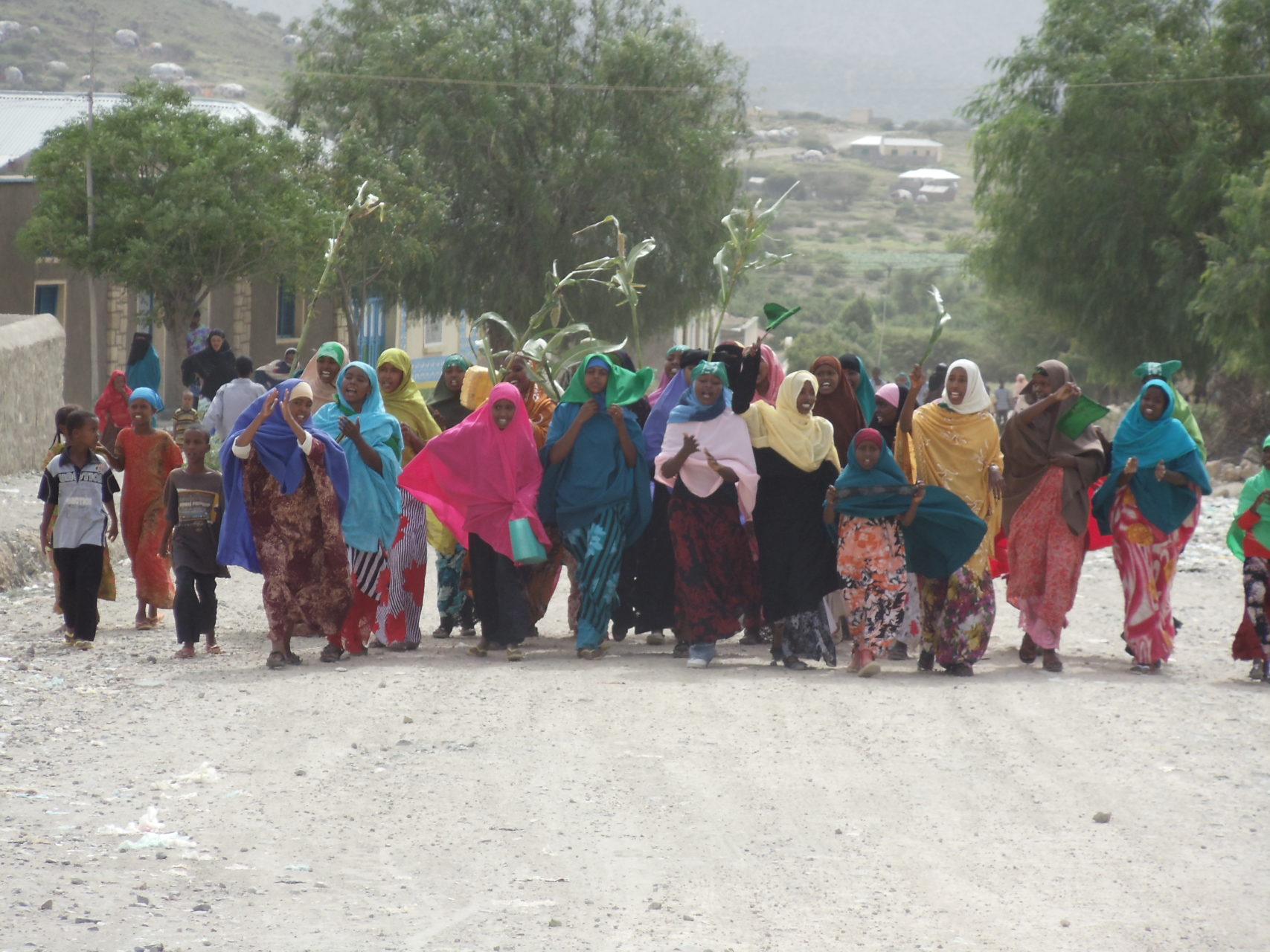 A group of women march happily down a dirt road