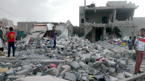 People stand in the midst of rubble following an airstrike in yemen