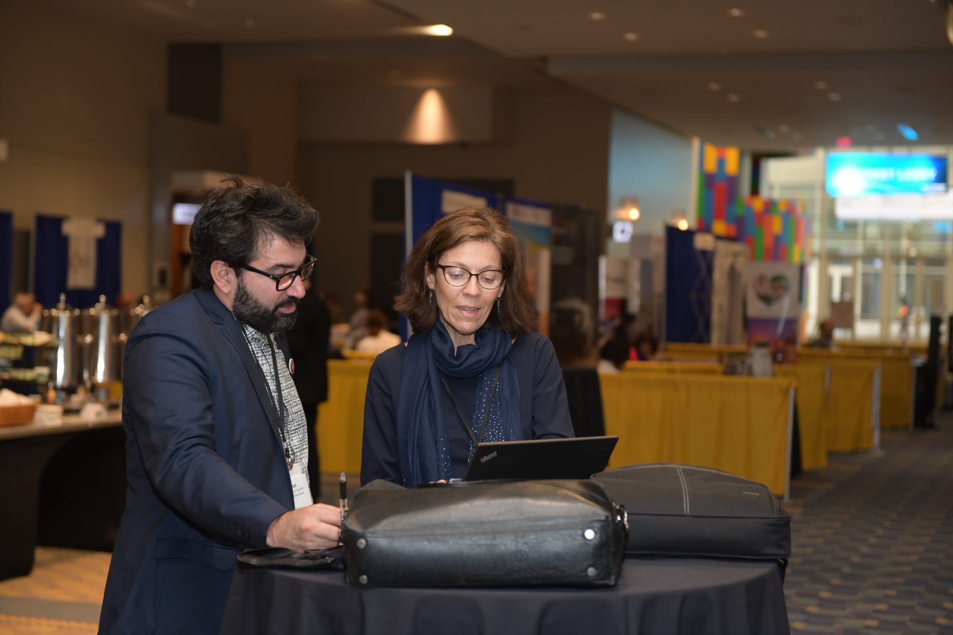 man and woman stand at high top table reading from a tablet.