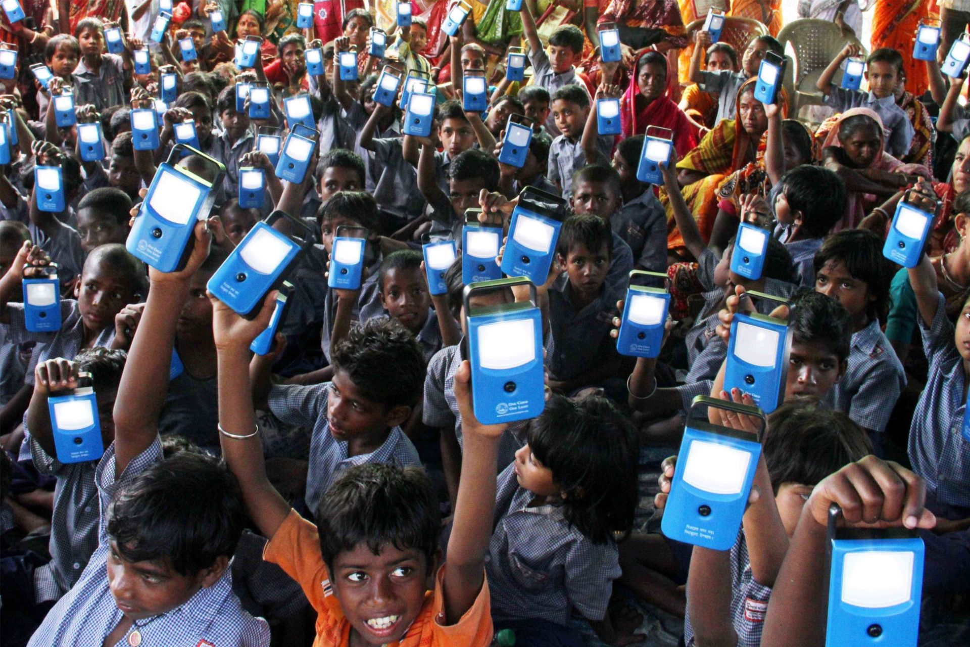 Young children raise their blue digital devices toward the sky.