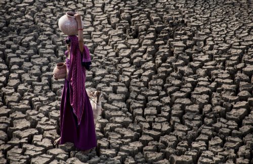 young girl carries water in her head and on her head in a water scarce environment