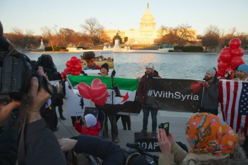 people at the tidal basin holding signs that say "with Syria"