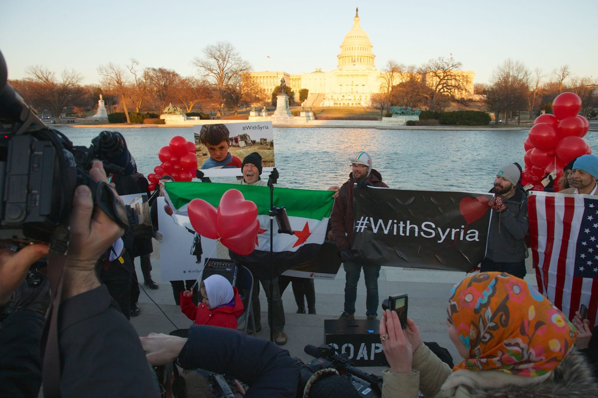 people at the tidal basin holding signs that say "with Syria"