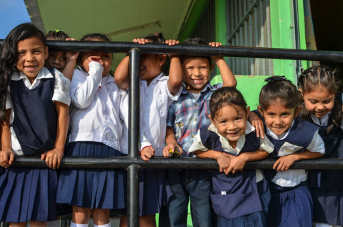school children stand at a railing smiling