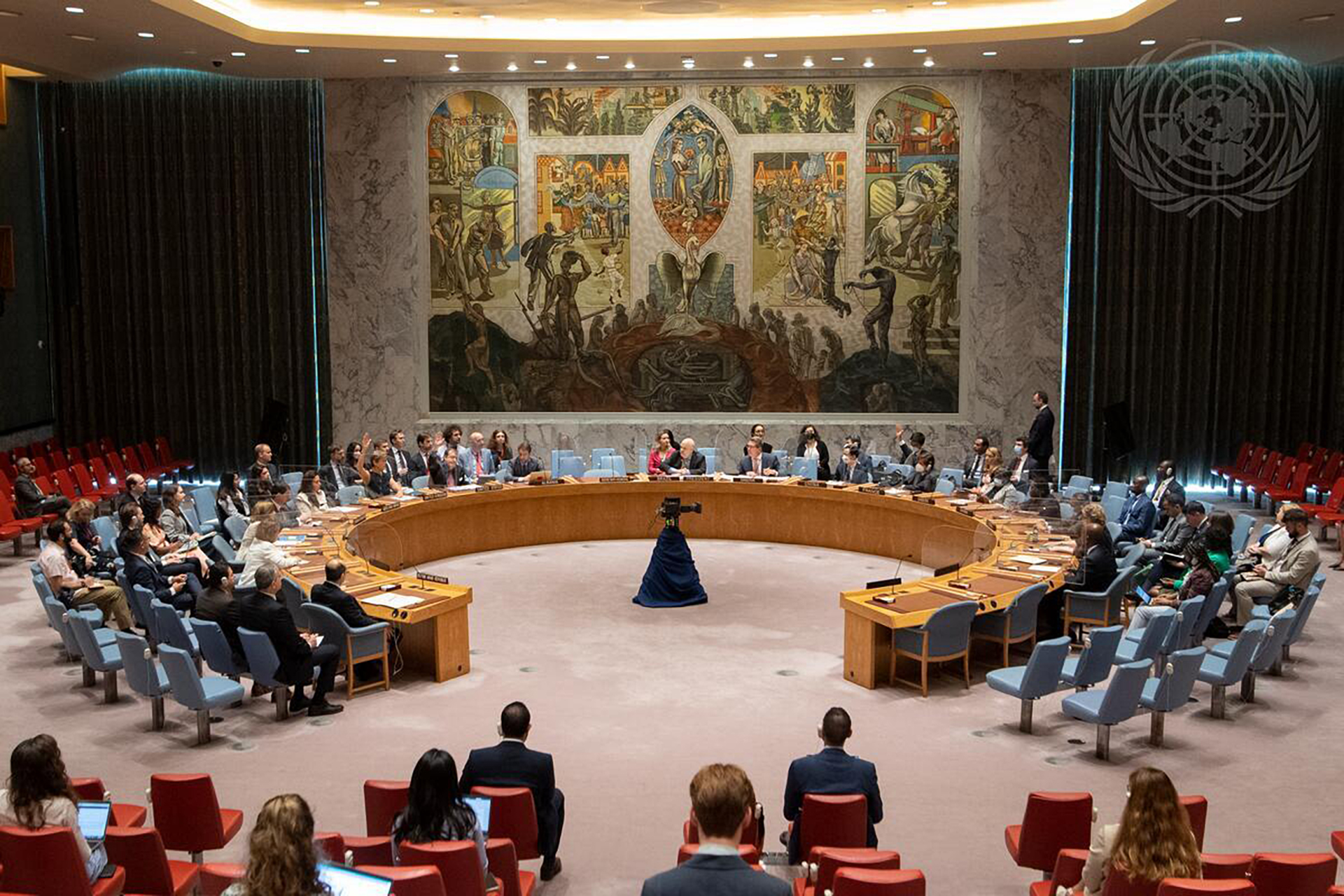 A view of UN Security Council members voting in favor of the resolution to extend resolution 2642 (2022) for six months. The photo is of the voting chamber. All council members are arranged in an open circle.
